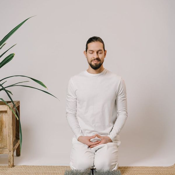 Person meditating peacefully in a calm, minimalist setting.